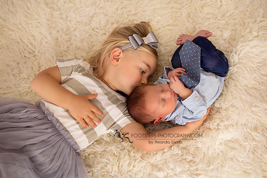 sibling and newborn kissing